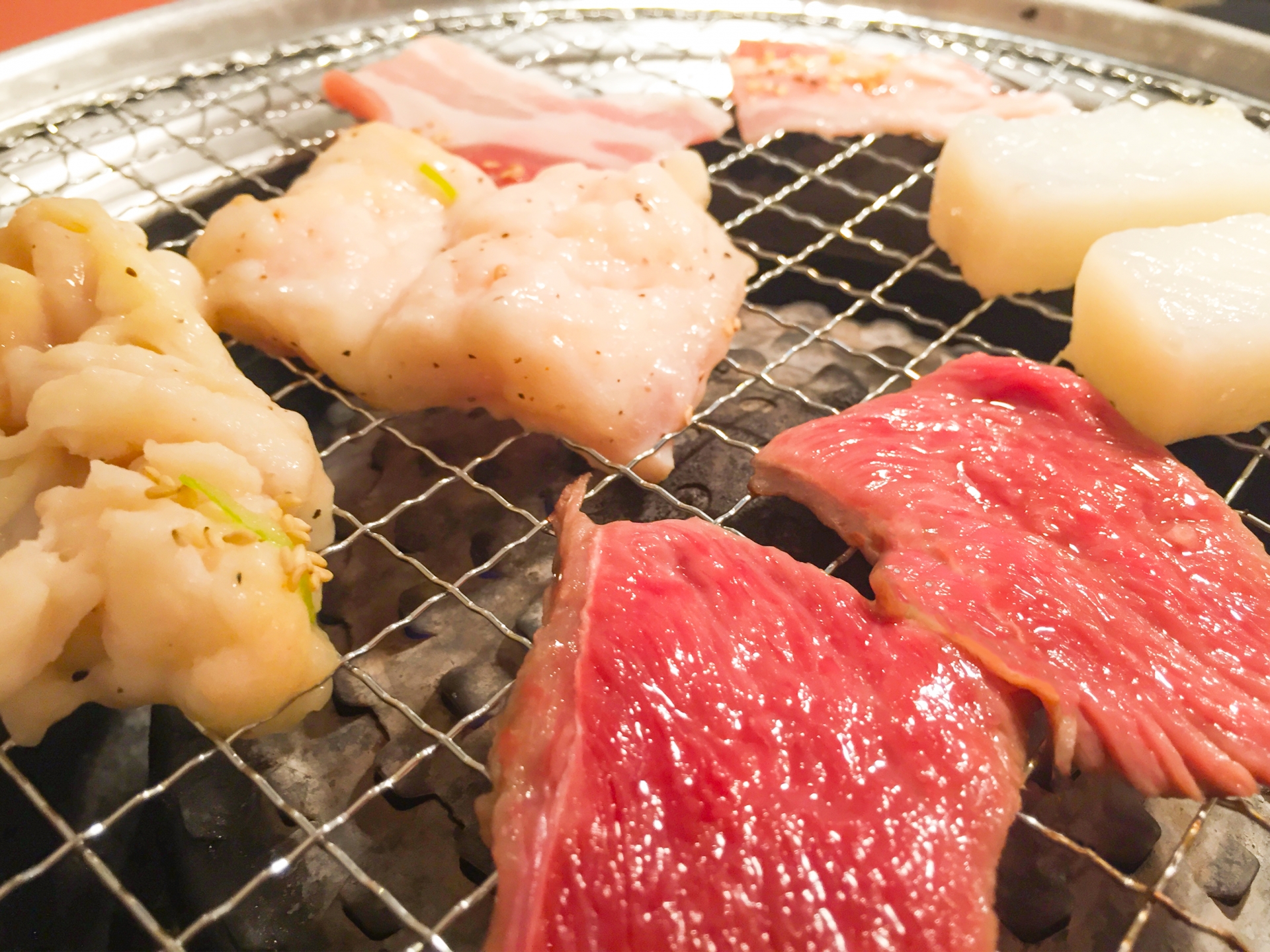 網の上で焼かれている様々な種類の肉とイカ